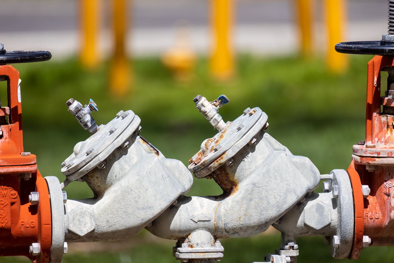Detailed view of rusted industrial gas valves outdoors on a sunny day.
